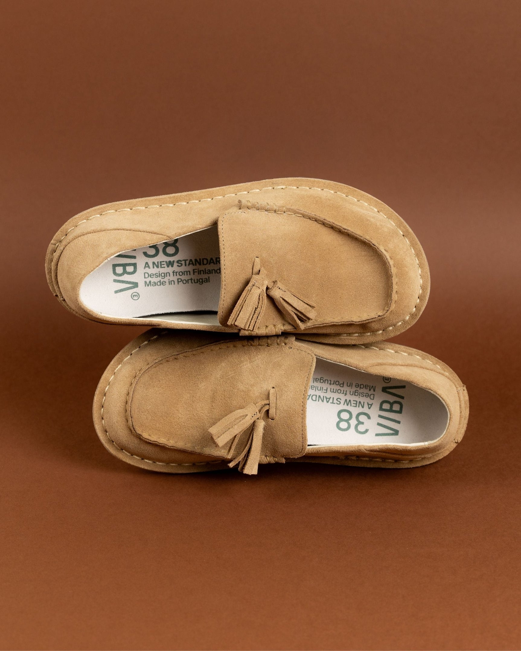 Pair of tan suede desert boots with tassel details and crepe soles, displayed from above.