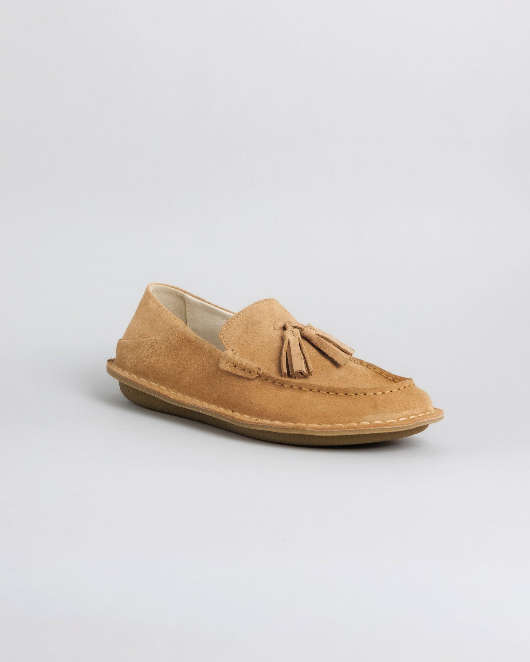 Tan suede loafer with tassel detail and crepe rubber sole, shown from the side.