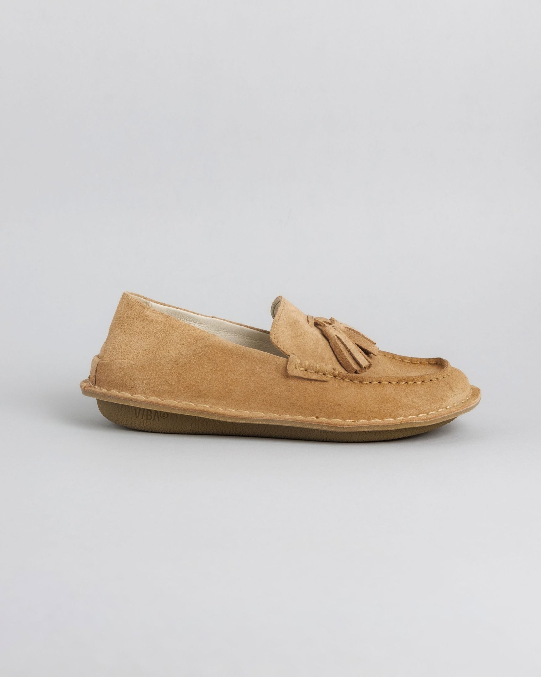 Tan suede loafer with tassel detail and crepe sole, shown from the side.